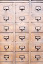 Surface of wooden cabinet with symmetrical rows of many drawers​ with metal handles