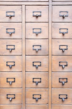 Surface of wooden cabinet with symmetrical rows of many drawers​ with metal handles