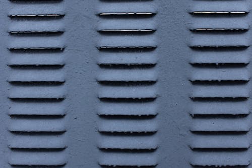 Background of gray shabby metal construction with symmetrical rows of ribs on surface