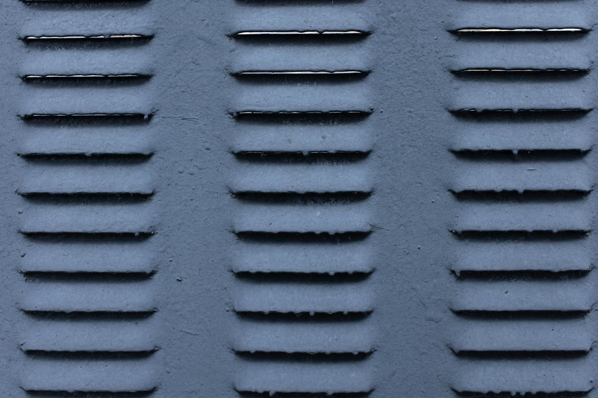 Background of gray shabby metal construction with symmetrical rows of ribs on surface