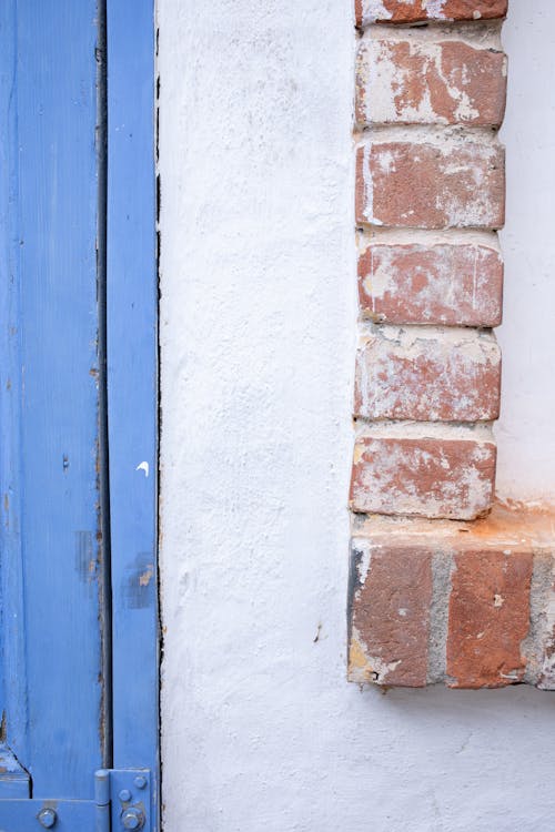 Textured background of aged shabby brick white stone wall and part of blue old wooden door