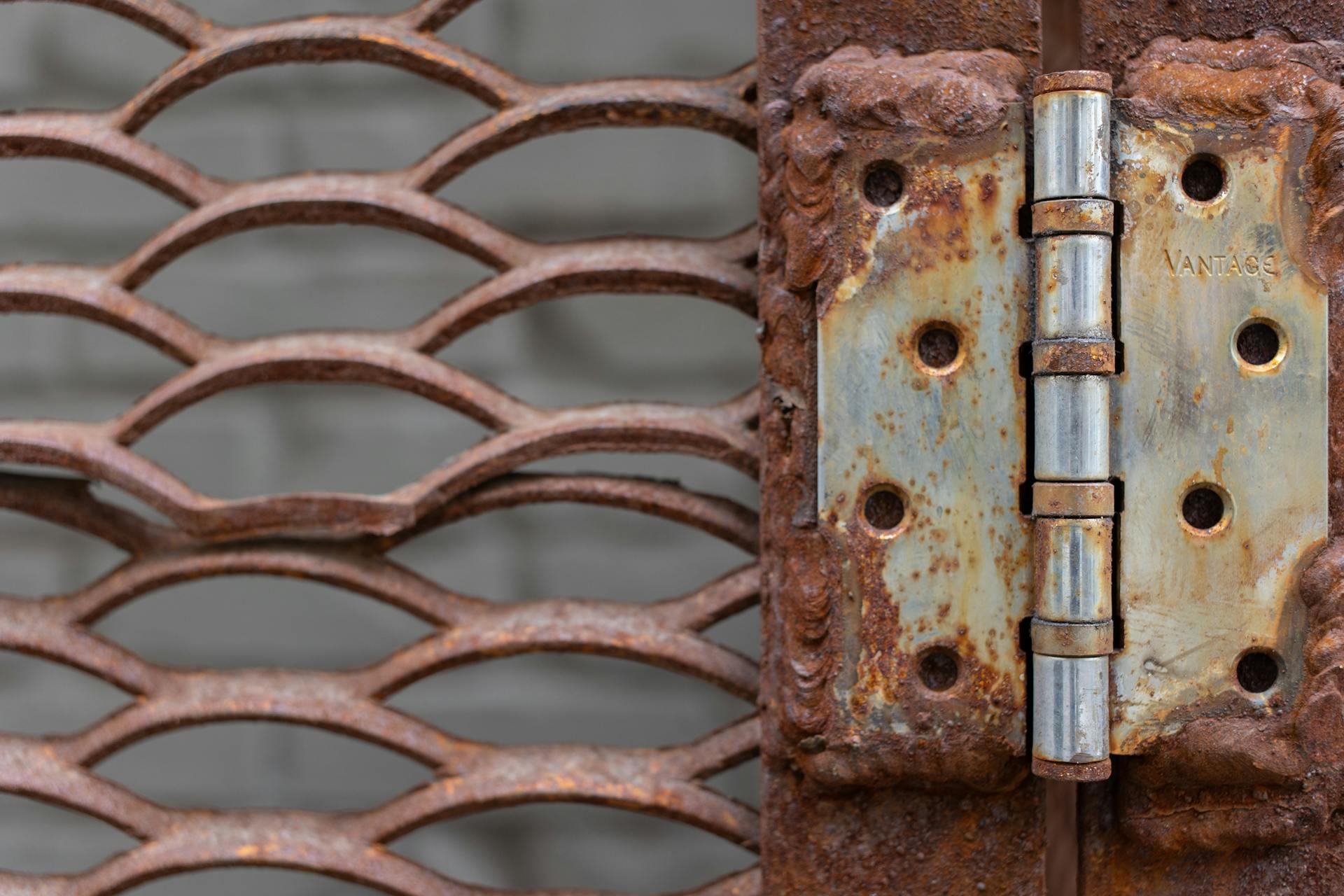Close-up of aged rusty metal lattice and hinged detail with corrosion.