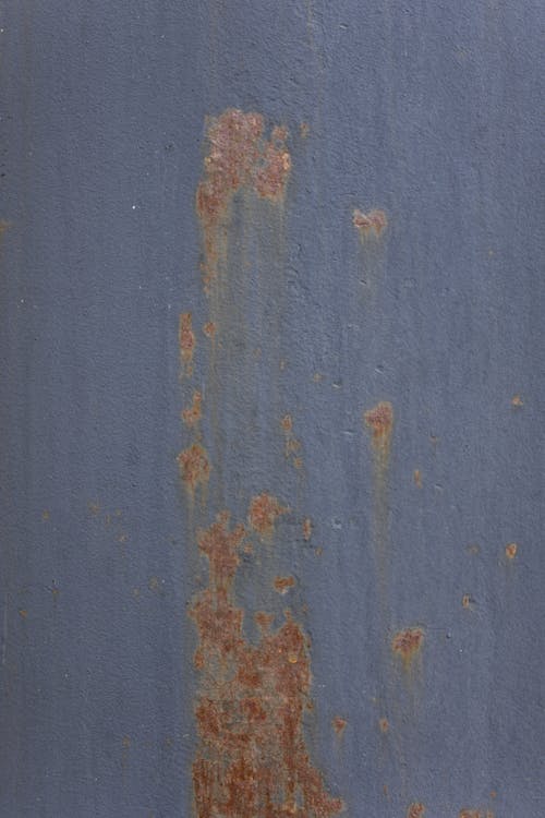 Textured background of weathered rough aged blue wall with peeling paint and scratches on surface