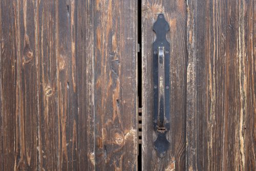 Free Closeup of weathered old rusty brown locked wooden door with cracks on surface with aged metal handle Stock Photo
