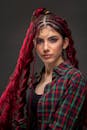 Trendy ethnic model with threads in braids on gray background