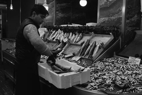 Grayscale Photo of a Man Working in Fish Market