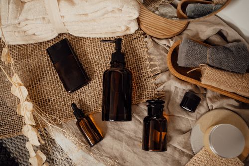 Free Elegant display of skincare and cosmetic bottles on a rustic background with dried flowers and towels. Stock Photo