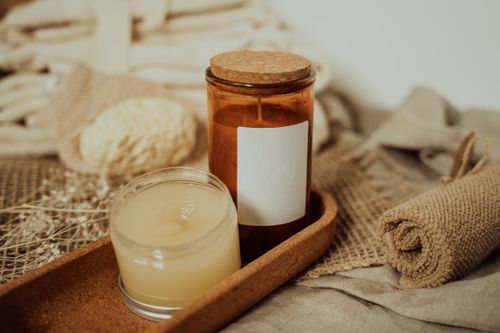 Free Close-up of candles and skincare products on linen and wooden tray for a soothing spa ambiance. Stock Photo