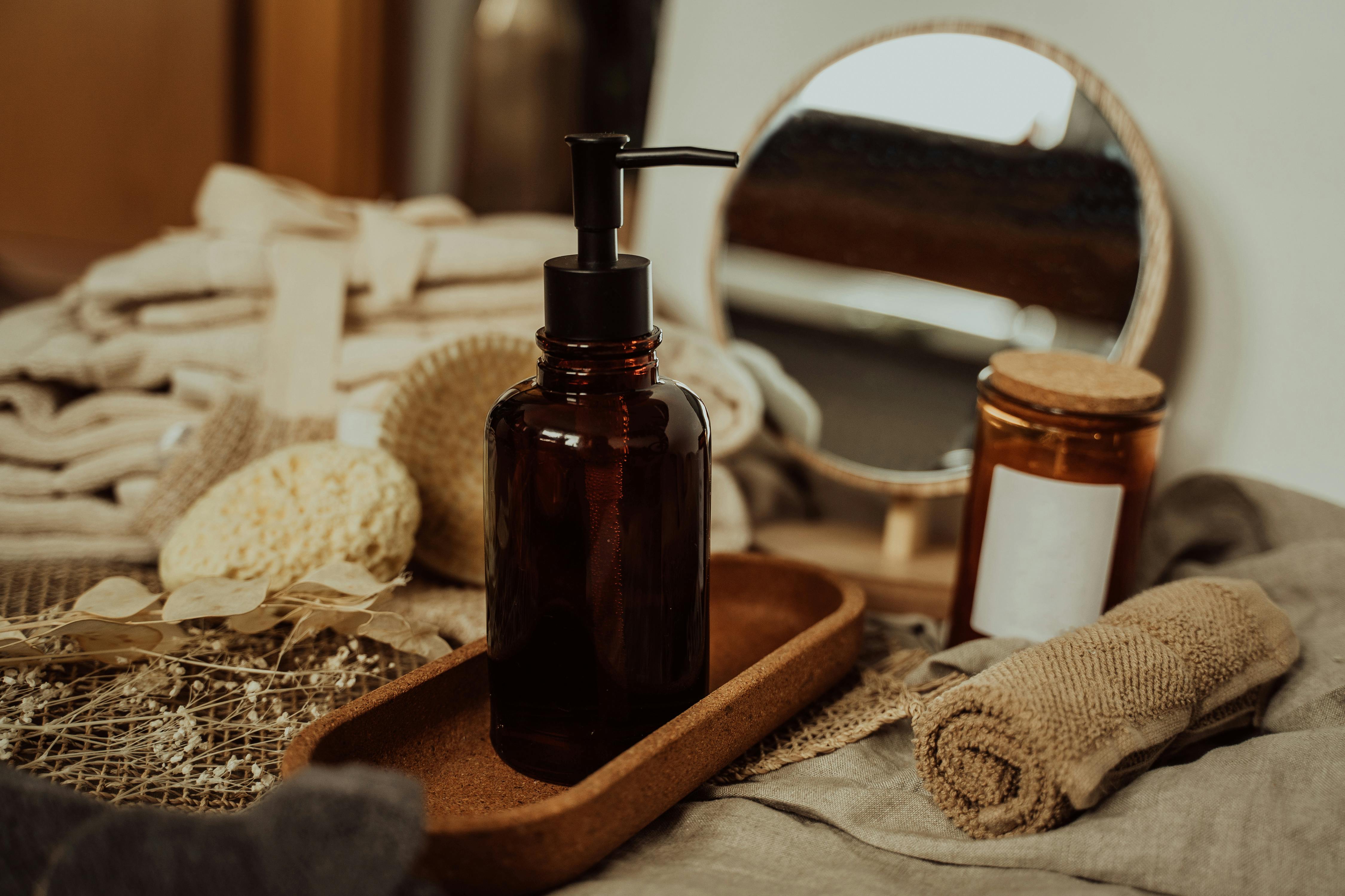 An image of oil in a glass pump bottle on a wooden tray 