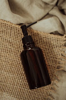 Close-up of an amber glass pump bottle on burlap, ideal for product presentations.