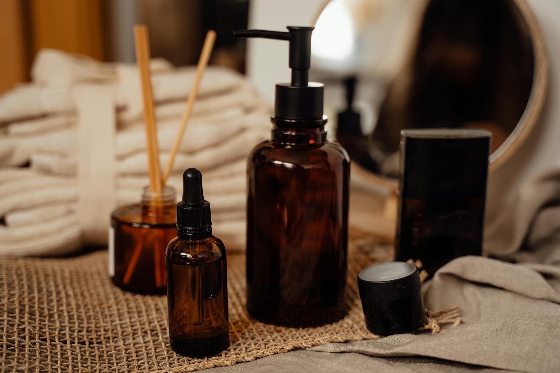 Rustic brown bottle display with cosmetics and essential oils on burlap indoors.