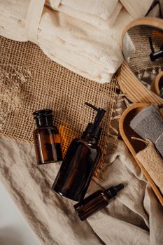 Cozy spa setup with brown bottles, towels, and wooden elements on a burlap background.