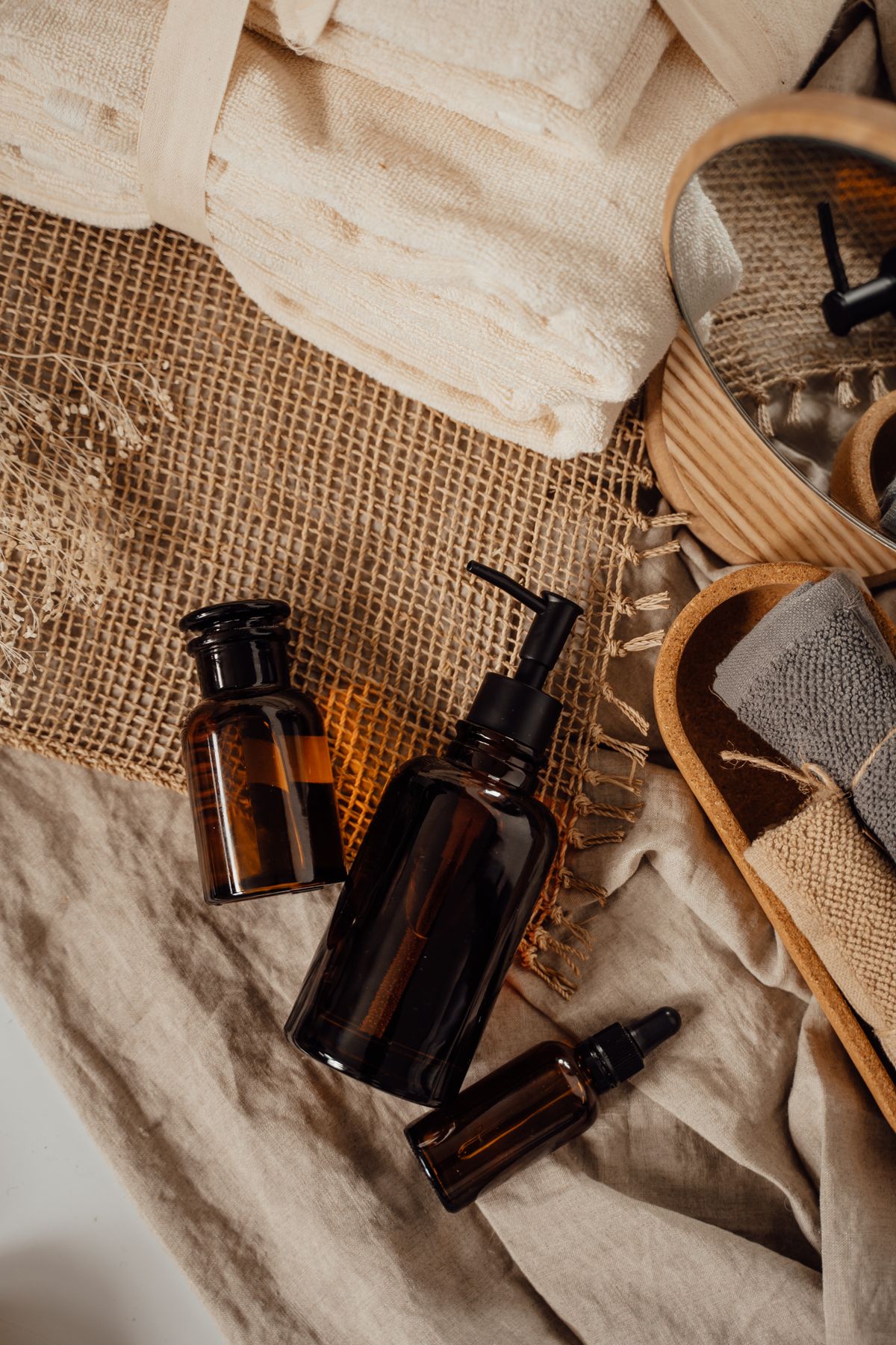 A flat lay of spa aftercare products with folded towels and amber bottles