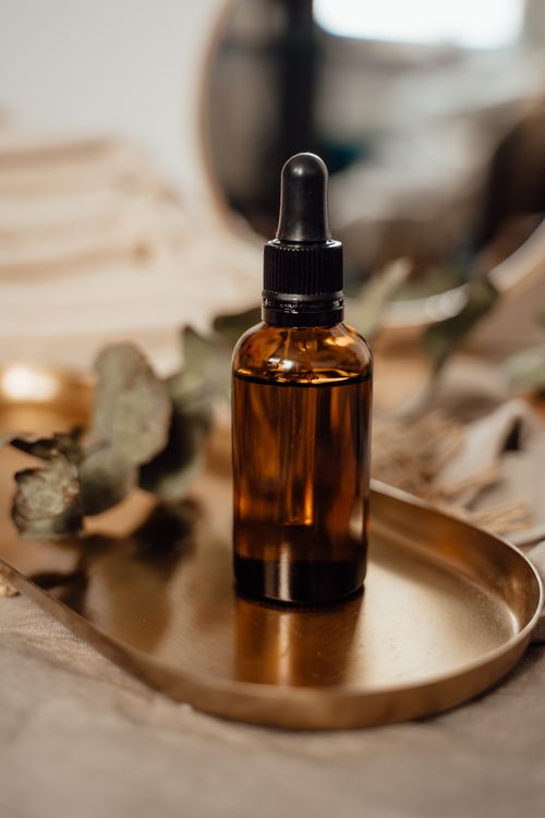 Free Amber glass dropper bottle on a wooden tray with a blurred natural background. Stock Photo