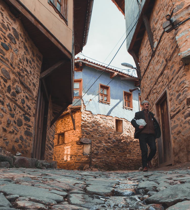 Old Man Walking In Stoned Village Street