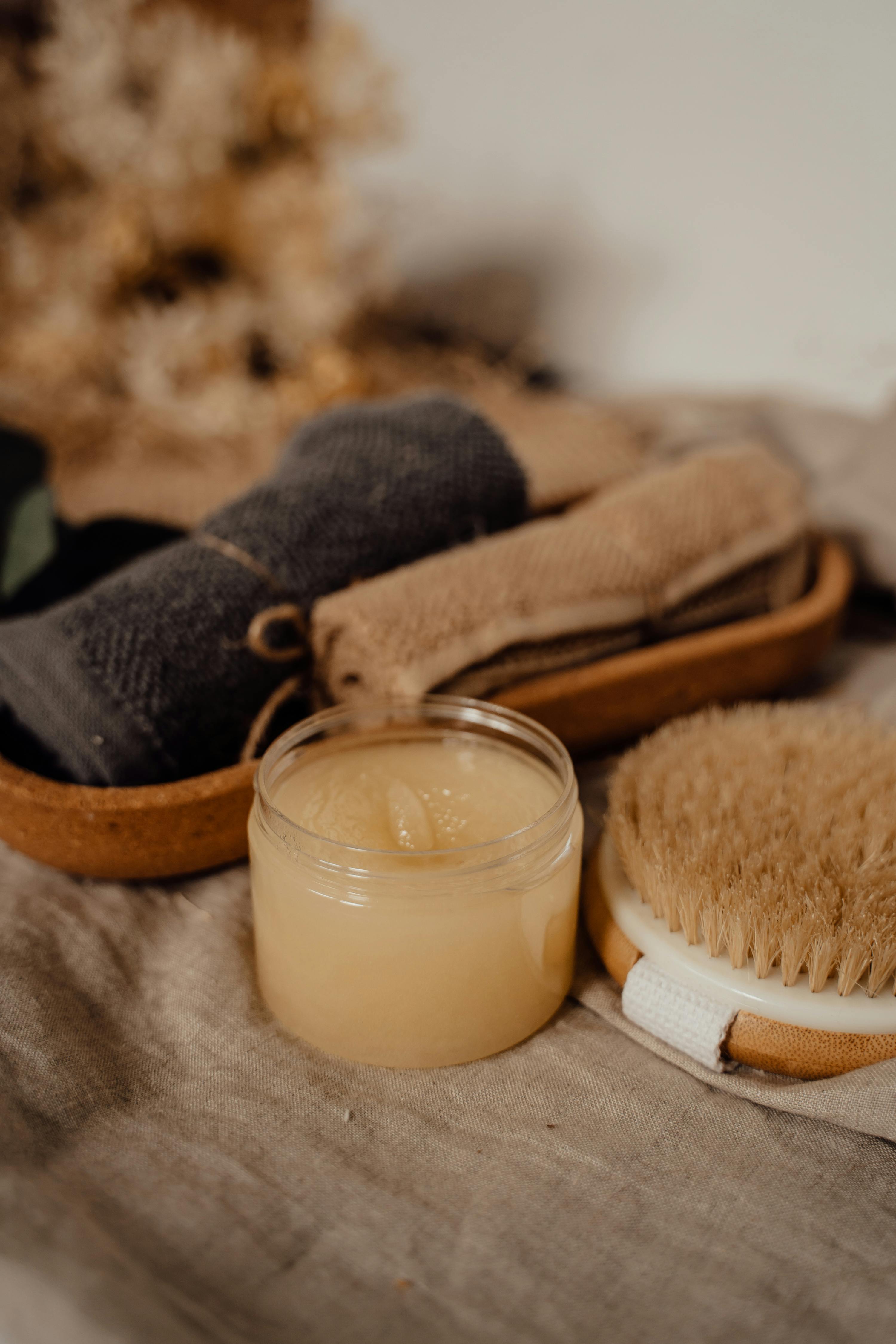 body scrub in plastic jar beside body brush