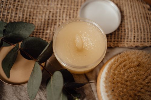 Free Close-up of a natural cosmetic product alongside eucalyptus leaves and a dry brush, perfect for skincare routines. Stock Photo