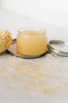 A soothing skincare jar with a sponge and dried flowers, perfect for health and wellness themes.