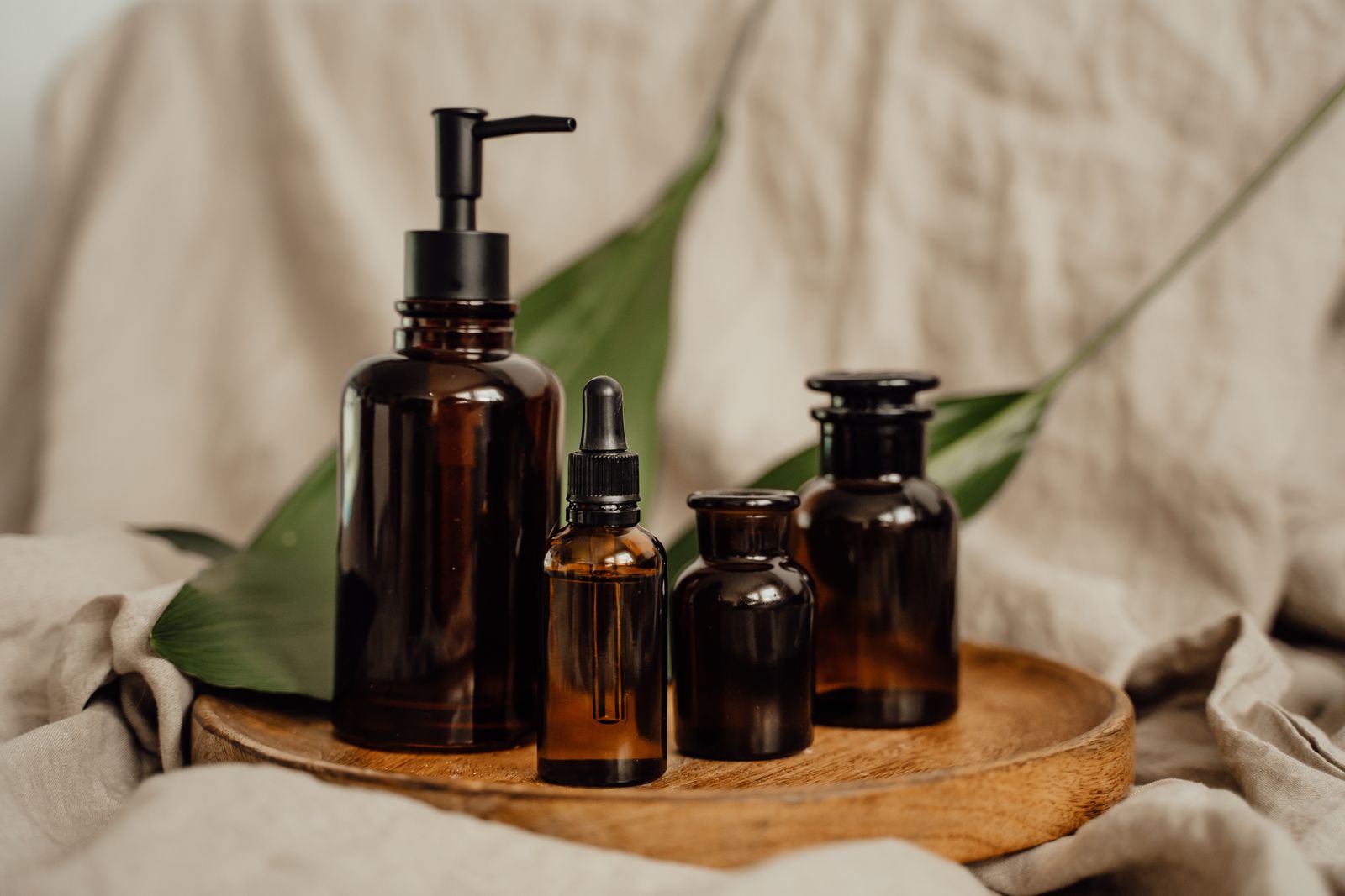 Amber apothecary bottles grouped on a wooden tray against soft linen — photo by Alesia Kozik on Pexels