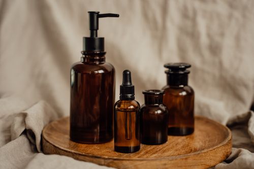 Free A collection of brown glass cosmetic bottles with a pump and pipette on a rustic wooden tray. Stock Photo