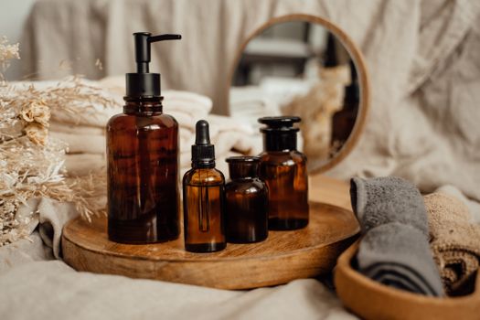 Stylish still life featuring brown glass bottles and towels on a wooden tray with a mirror backdrop.