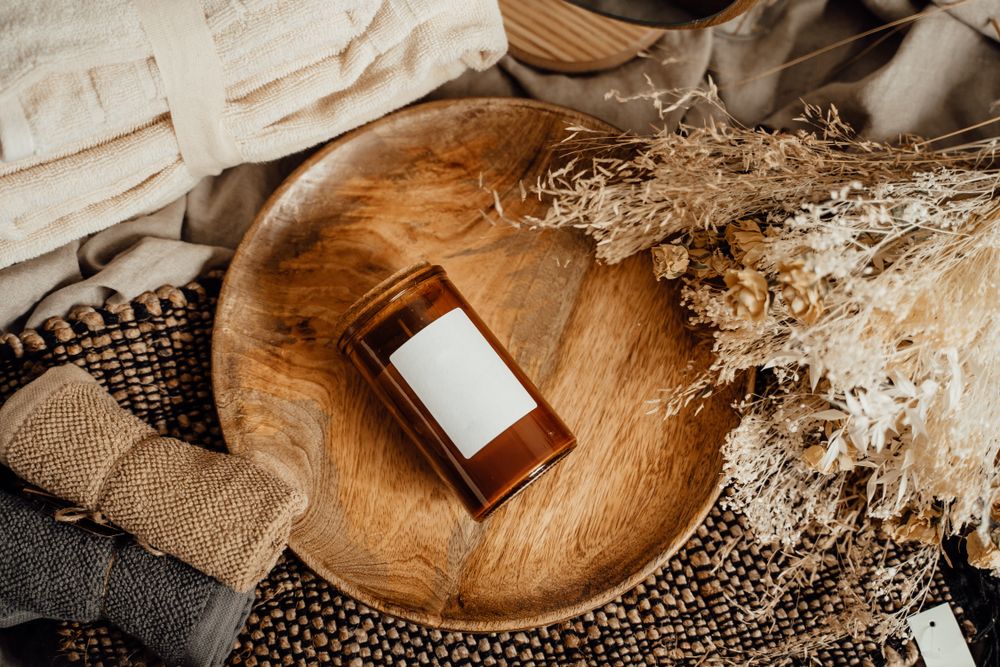 Vela aromática sobre bandeja de madera con textiles de spa
