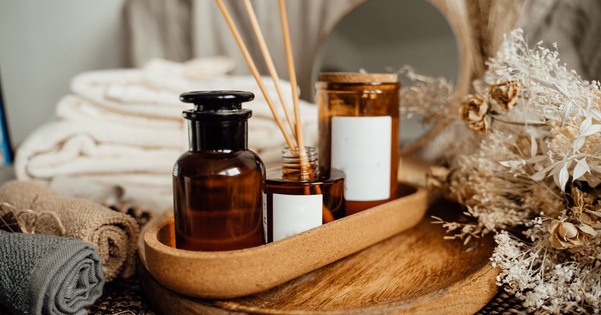 Self-care products arranged on a wooden tray with candles and towels