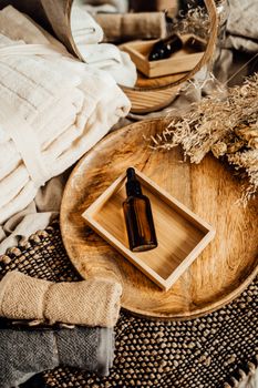Elegant spa composition featuring glass dropper bottle, dried flowers, and warm wooden elements for a serene ambiance.