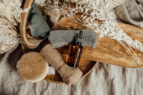 Bottle With Dropper and Rolled Face Towels on a Wooden Tray