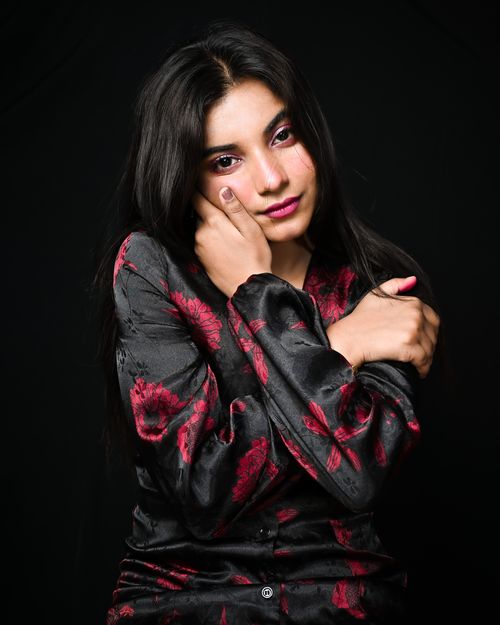 Free Young woman in floral blouse posing in studio with black background, showcasing elegance and beauty. Stock Photo