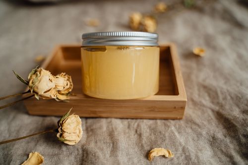 Free A close-up of a cosmetic jar placed on a wooden tray surrounded by dried flowers, emphasizing a natural, rustic aesthetic. Stock Photo
