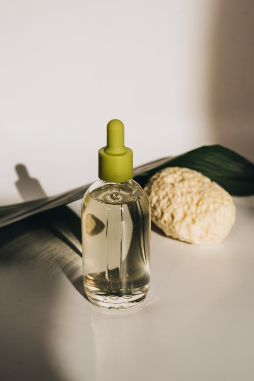 Glass Bottle of Massage Oil and a Beige Sponge