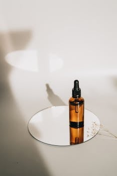 Elegant glass serum bottle on a round mirror with a soft shadow backdrop.