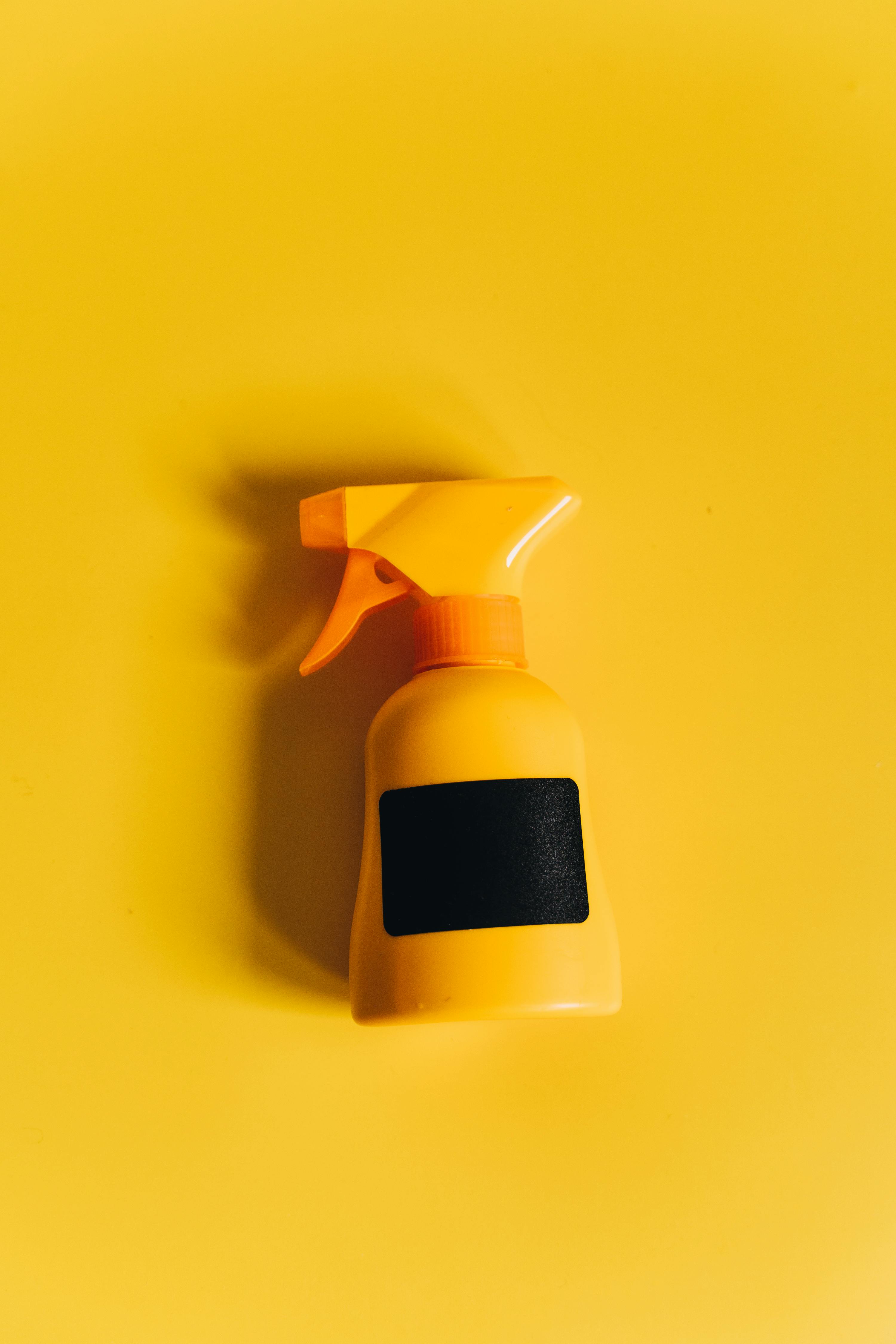 Minimalistic flat lay of a yellow spray bottle on a vibrant matching surface. Perfect for product photography.