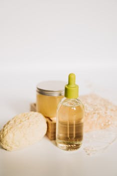 Minimalist arrangement of a cosmetic dropper bottle with natural textures and gentle lighting.