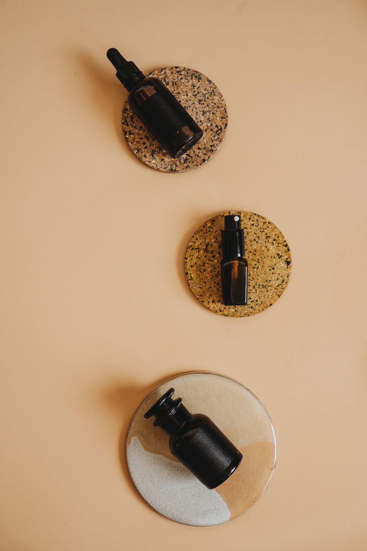 Amber dropper bottles arranged on neutral ceramic coasters