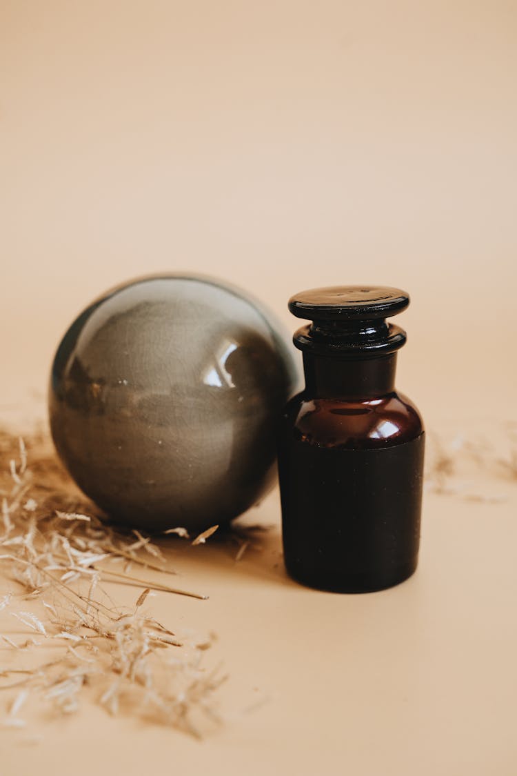 Brown Glass Bottle Near Round Shiny Object