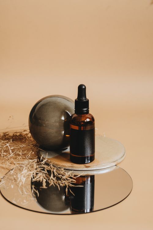 Free Aesthetic display of a cosmetic oil bottle with natural elements on a mirrored surface. Stock Photo