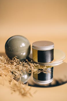 Aesthetic display of a cosmetic container with dried leaves and reflections, suitable for skincare branding.