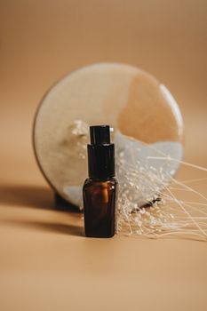 Elegant brown glass serum bottle on beige backdrop with artistic vase. Ideal for modern skincare and cosmetics imagery.