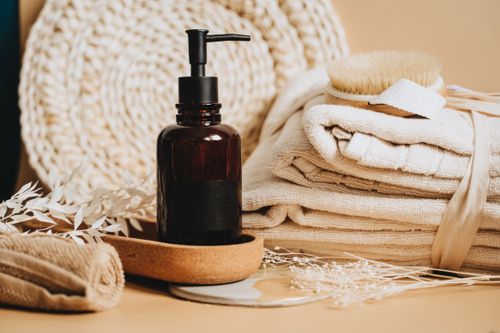 Free A serene spa-themed composition featuring a pump bottle, towels, brush, and natural elements for a relaxing atmosphere. Stock Photo