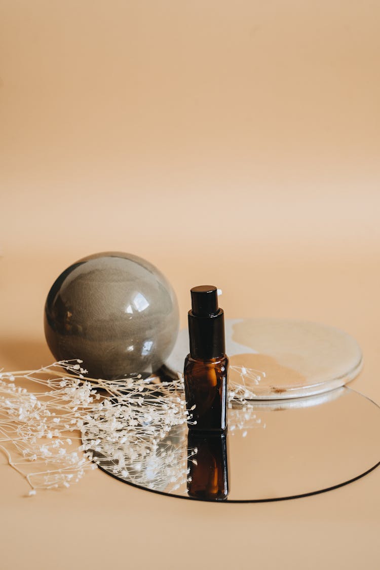 A Marble Ball And A Brown Spray Bottle On A Round Mirror Tray