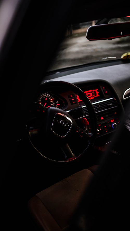 Free Close-up shot of a sleek Audi car interior featuring a illuminated dashboard and steering wheel in dim light. Stock Photo
