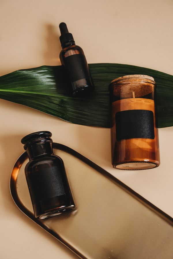 Candle, dropper bottle and jar arranged on stone — photo by Alesia Kozik on Pexels
