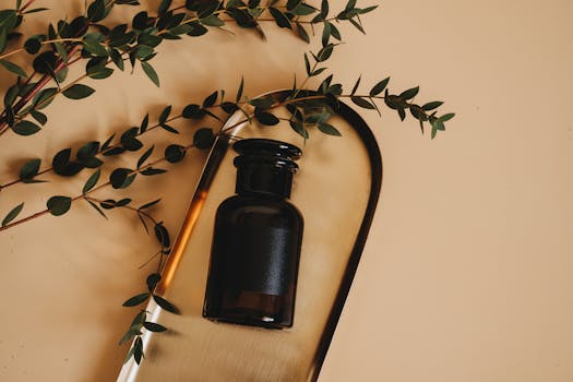 Stylish flat lay of a dark glass cosmetic bottle on a tray with green leaves, perfect for wellness themes.