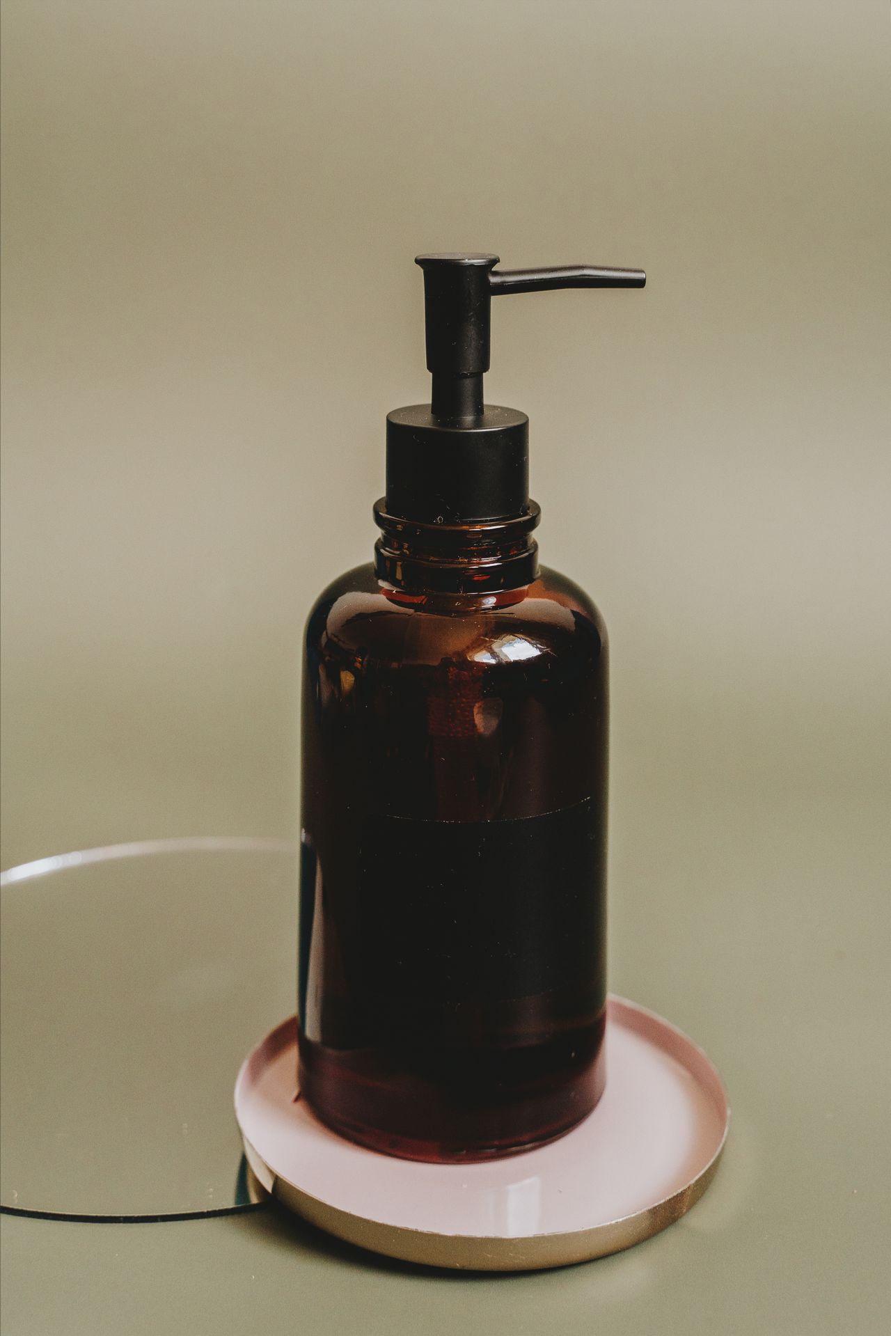 Amber glass soap dispenser with a black pump on a small tray