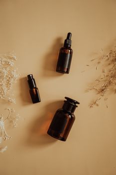 Stylish flat lay of amber bottles with dry floral accents, perfect for beauty product presentation.