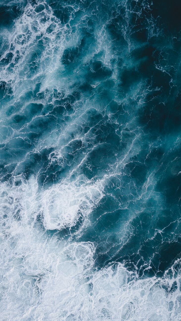 Aerial perspective of ocean waves crashing and foaming, beautifully capturing sea's dynamic energy.