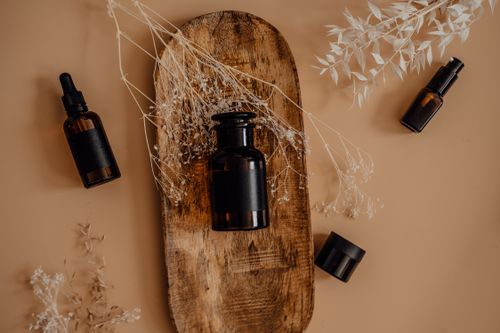 Free Flat lay of brown glass bottles on wooden tray with dried plants, ideal for natural skincare themes. Stock Photo
