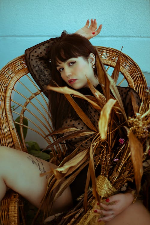 Woman in Black Top Sitting on Brown Wicker Chair